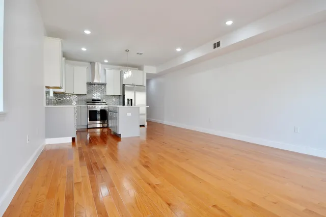 a kitchen with stainless steel appliances granite countertop a sink a stove a refrigerator and island with wooden floor