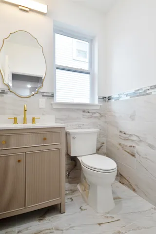 a bathroom with a granite countertop sink a toilet and a mirror