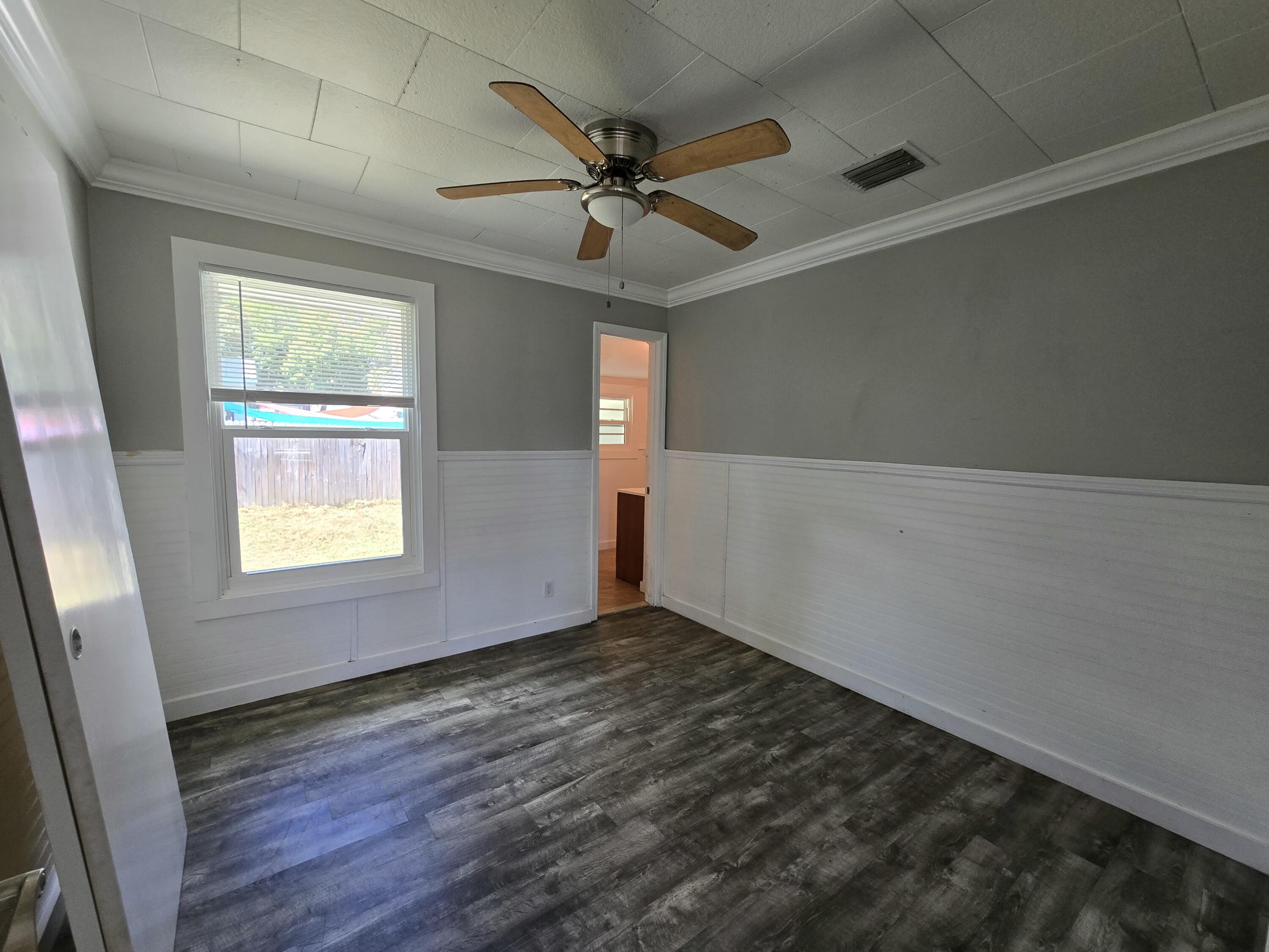 820 Southwest Palm City Road Stuart, FL 34994 - Photo 11 of 24 an empty room with wooden floor fan and windows