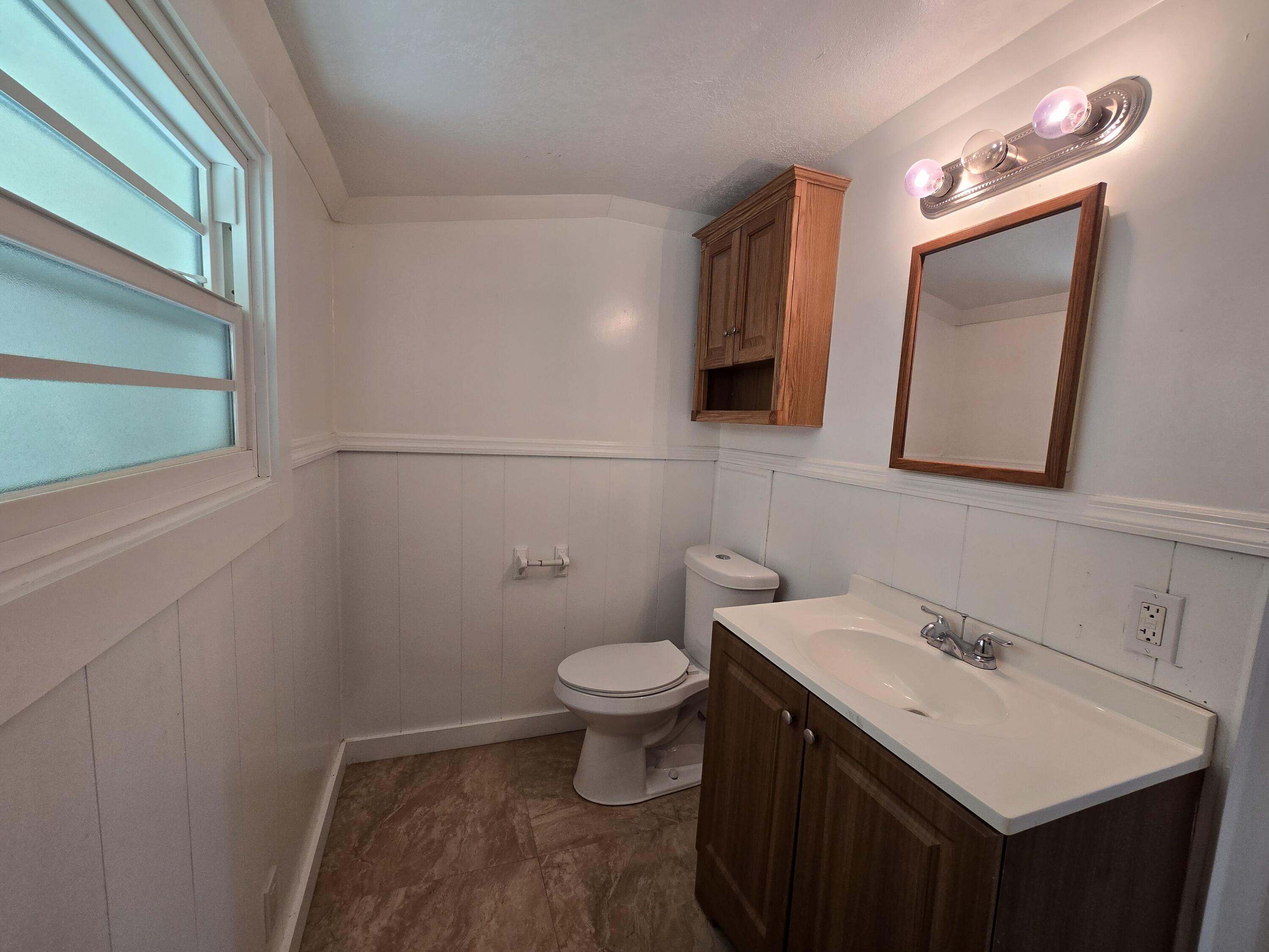820 Southwest Palm City Road Stuart, FL 34994 - Photo 12 of 24 a bathroom with a toilet a sink a vanity and mirror