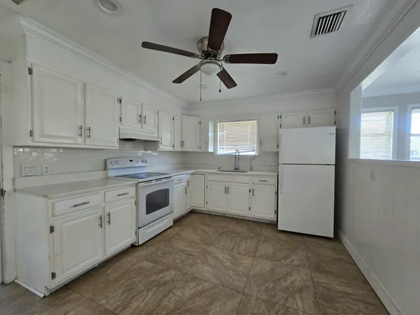 a kitchen with white cabinets and window