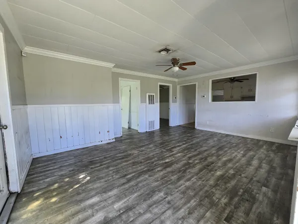 an empty room with wooden floor fan and windows