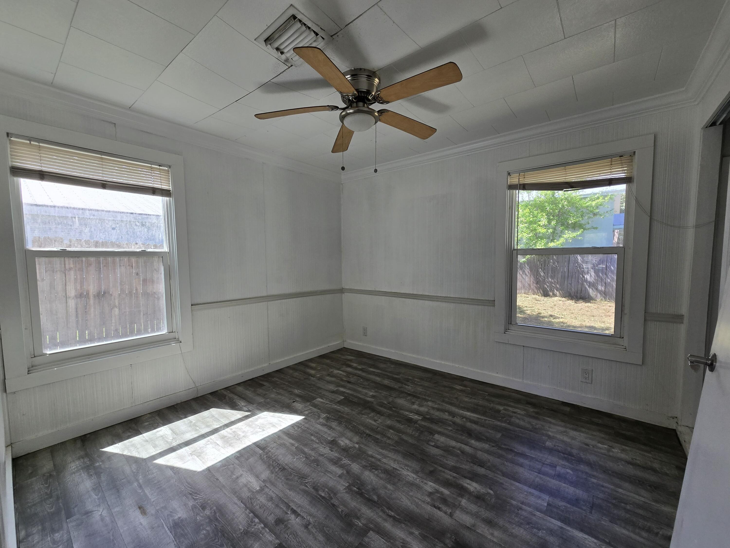 820 Southwest Palm City Road Stuart, FL 34994 - Photo 10 of 24 an empty room with wooden floor fan and windows