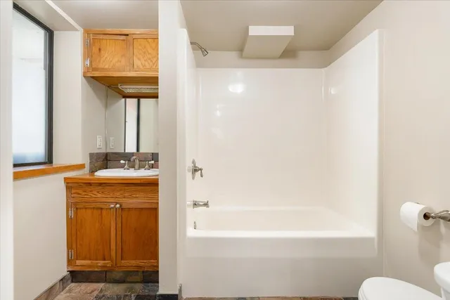 a bathroom with a granite countertop sink a toilet and bathtub