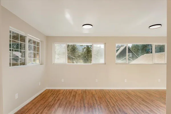 an empty room with wooden floor and windows