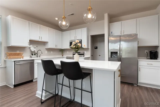 a kitchen with a refrigerator a sink dishwasher a stove and white cabinets with wooden floor