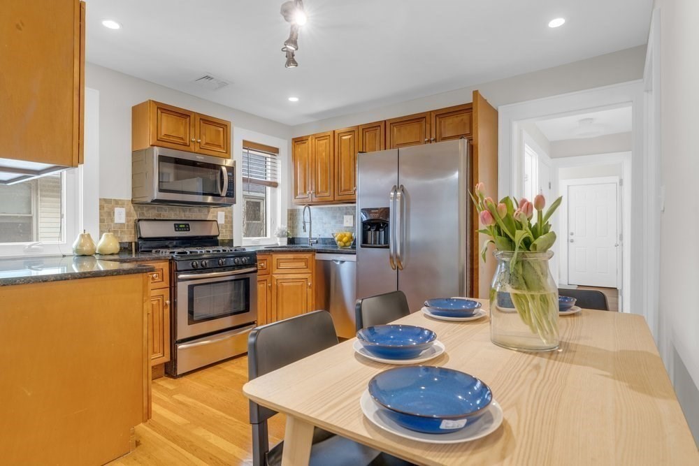 35 Boulevard Road, Unit 35 Arlington, MA 02474 - Photo 7 of 20 a kitchen with stainless steel appliances granite countertop a refrigerator a stove a sink dishwasher a dining table and chairs with wooden floor