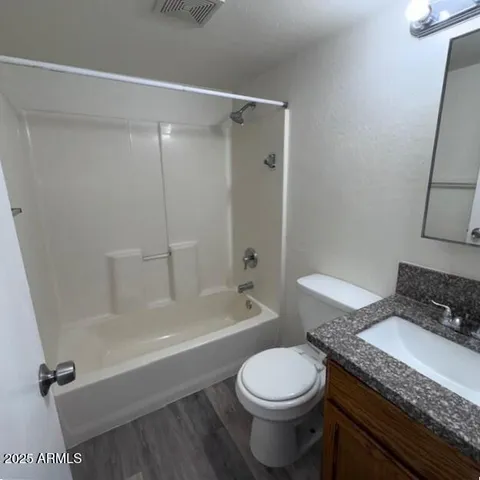 a bathroom with a granite countertop bathtub shower sink vanity and toilet