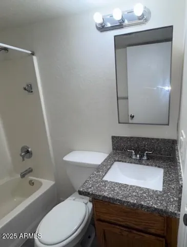 a bathroom with a granite countertop sink a toilet and bathtub