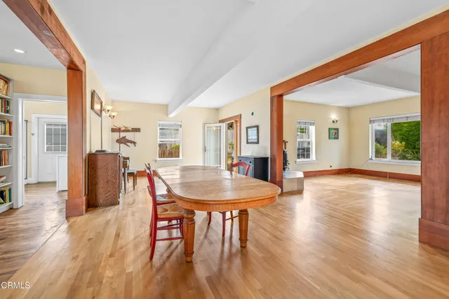 a dining room with wooden floor a chandelier a wooden table and chairs