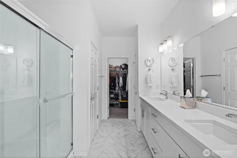 a spacious bathroom with a double vanity sink a large mirror and shower