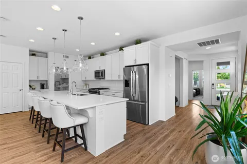 a kitchen with stainless steel appliances a refrigerator a stove a sink dishwasher and a dining table with wooden floor