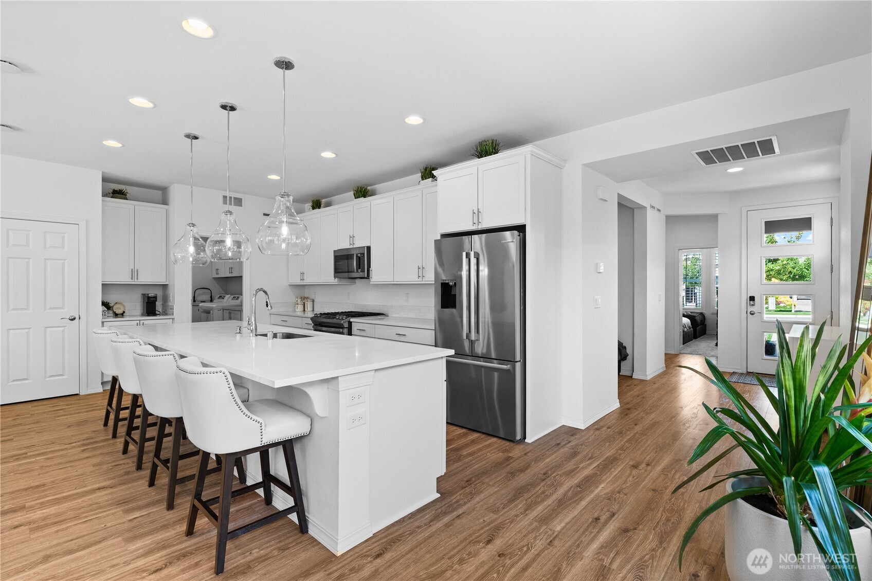 15215 182nd Avenue East Bonney Lake, WA 98391 - Photo 6 of 40 a kitchen with stainless steel appliances a refrigerator a stove a sink dishwasher and a dining table with wooden floor