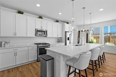 a kitchen with kitchen island a stove a table and chairs in it