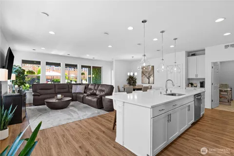 a view of a kitchen with kitchen island a large counter top space a sink stainless steel appliances and living room view