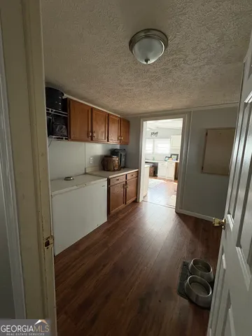 a kitchen with a wooden floor and a view of living room