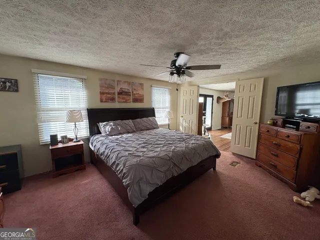a spacious bedroom with a bed and a flat screen tv