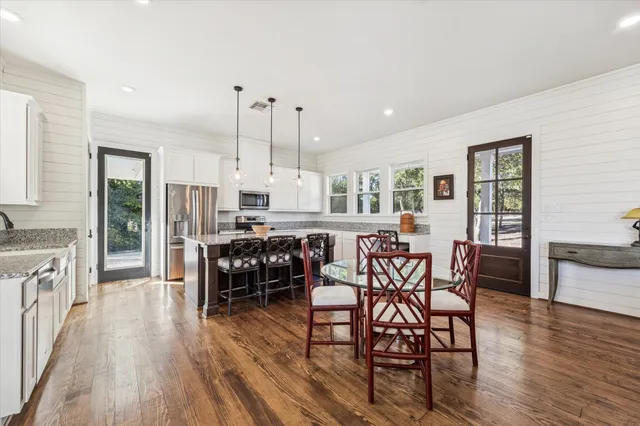 a kitchen with stainless steel appliances a dining table chairs stove and white cabinets