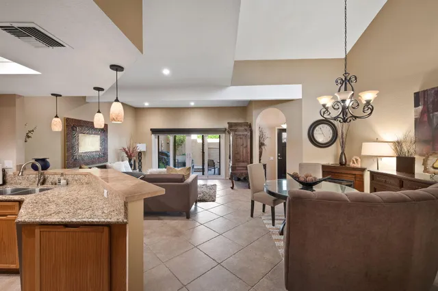 a large living room with granite countertop furniture a chandelier and kitchen view