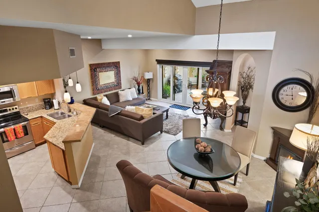 a living room with couches a fireplace and a dining table with wooden floor