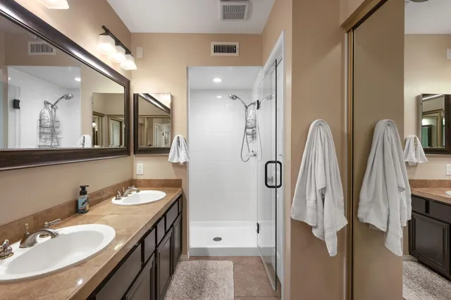 a bathroom with a double vanity sink a mirror and shower
