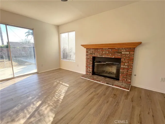 an empty room with wooden floor fireplace and windows