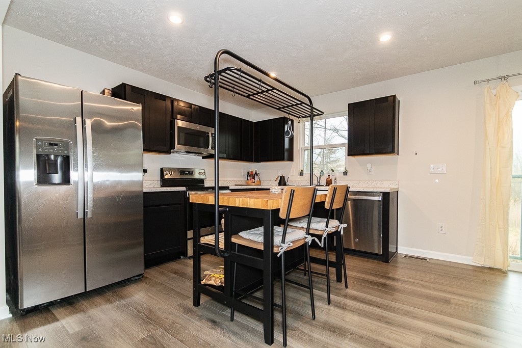 Kitchen with a textured ceiling, light wood-type flooring, and stainless steel appliances