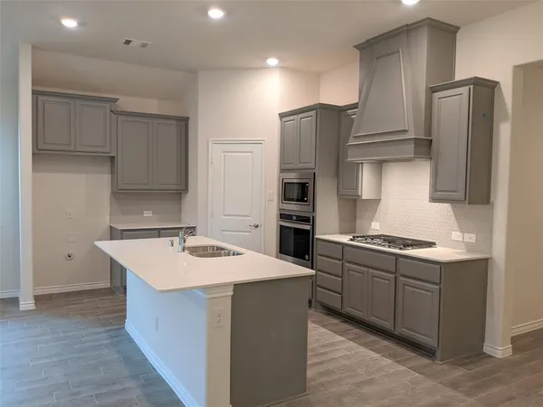 a kitchen with stainless steel appliances a sink stove refrigerator and cabinets