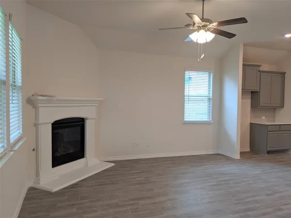 a view of a livingroom with a fireplace a ceiling fan and windows
