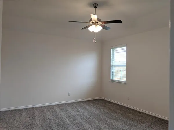 an empty room with a chandelier fan and windows