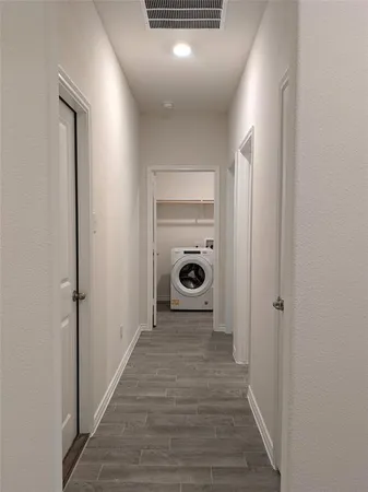 a view of a hallway with a wooden floor and a washing machine