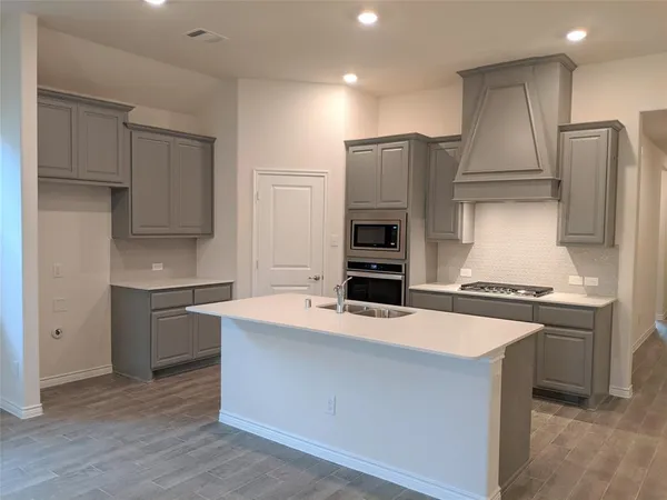 a kitchen with kitchen island stainless steel appliances a stove refrigerator sink and microwave