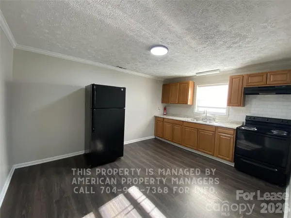 a kitchen with granite countertop a refrigerator and a stove top oven