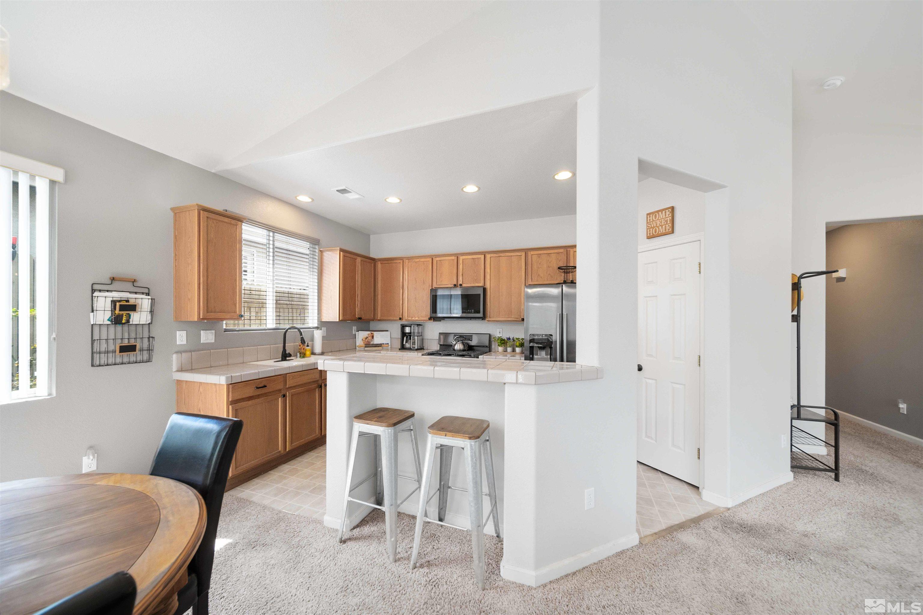 10599 Iron Point Circle Reno, NV 89521 - Photo 10 of 39 a kitchen with stainless steel appliances granite countertop a refrigerator a stove a sink a dining table and chairs with wooden floor