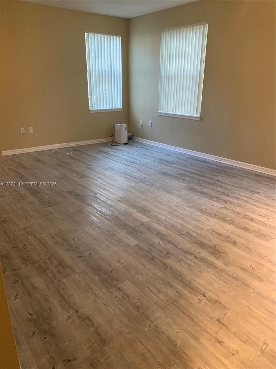 6572 West Sample Road, Unit 6572 Coral Springs, FL 33067 - Photo 13 of 17 an empty room with wooden floor and windows