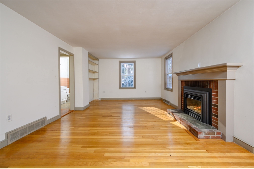 15 Autumn Circle Hingham, MA 02043 - Photo 12 of 38 a view of empty room with wooden floor and fireplace