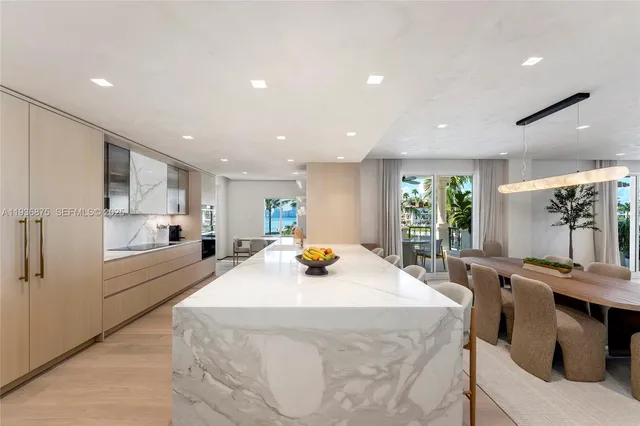 a kitchen with stainless steel appliances a stove a sink a refrigerator white cabinets and couches with wooden floor