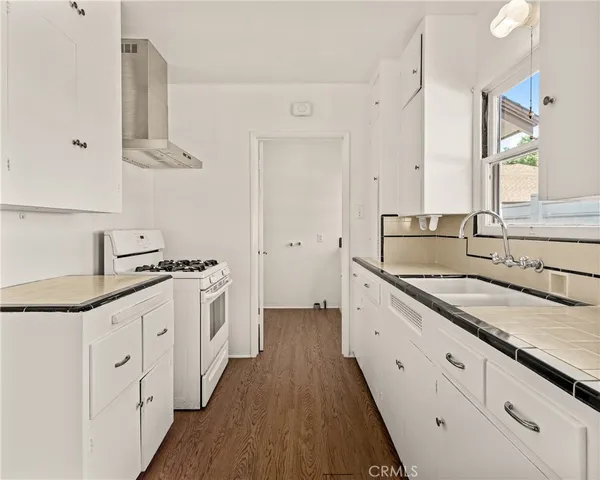 a large kitchen with a lot of counter space and wooden floor