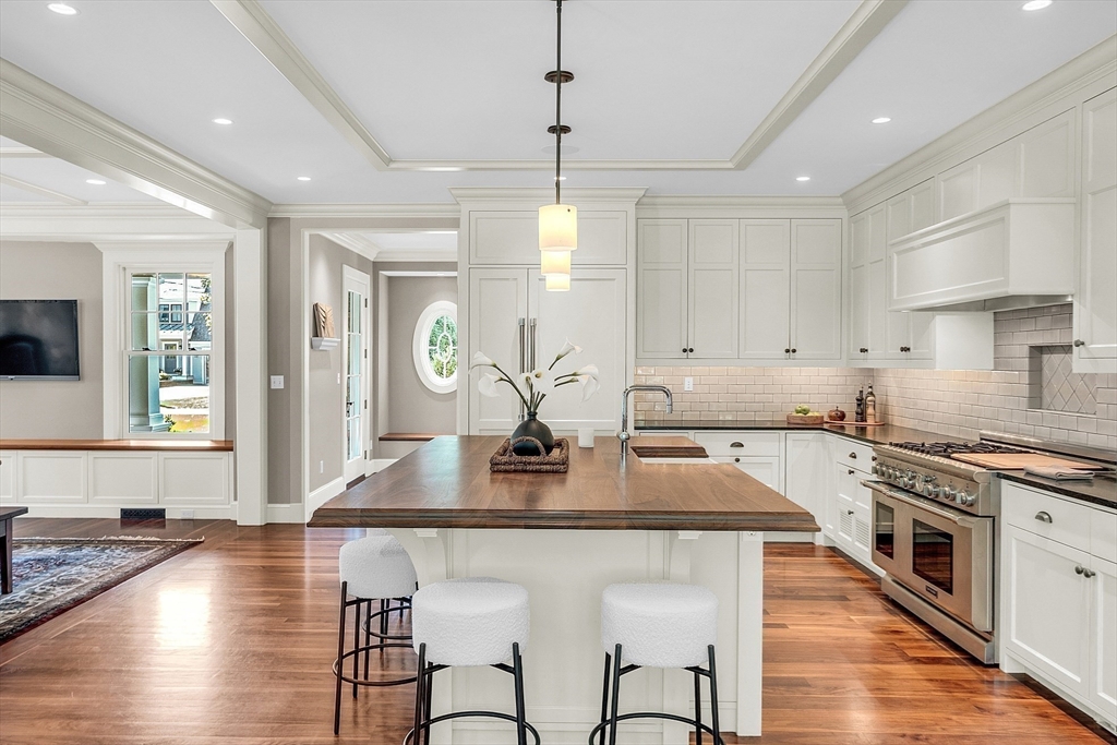 247 Independence Road Concord, MA 01742 - Photo 9 of 42 a kitchen with kitchen island granite countertop a stove a sink a dining table and chairs