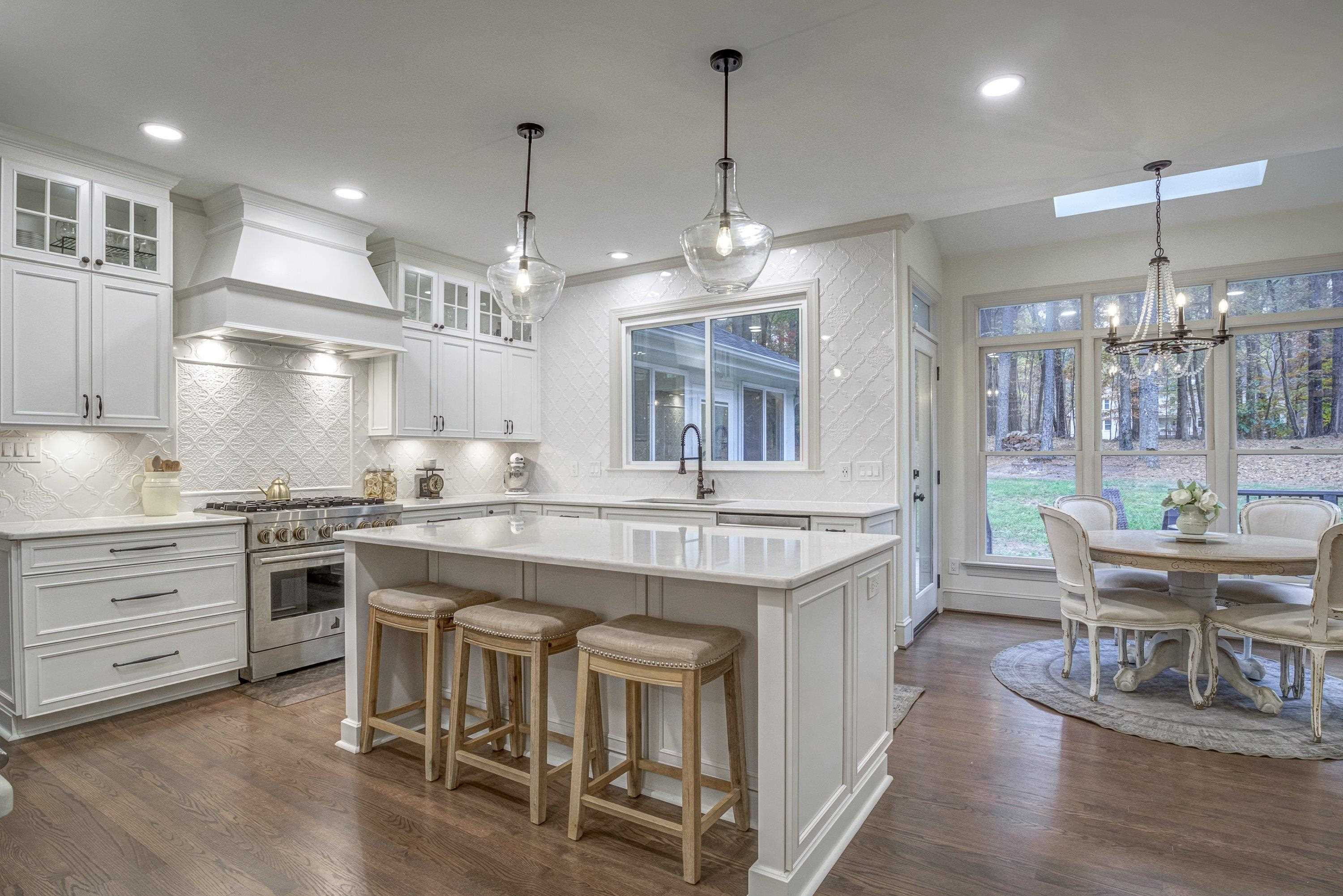 1413 Paumier Court Raleigh, NC 27615 - Photo 24 of 61 a kitchen with kitchen island a dining table chairs sink and wooden floor