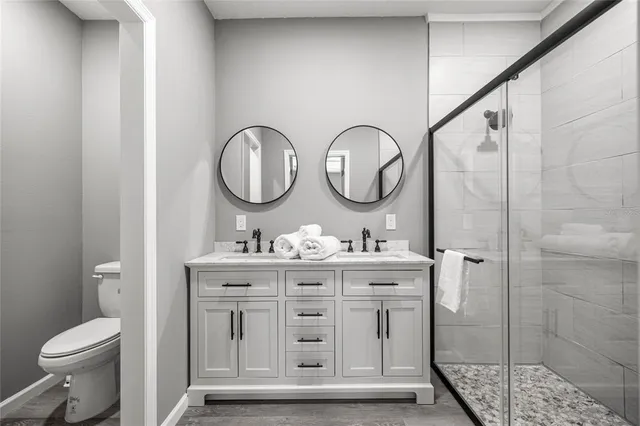 a bathroom with a toilet a sink a mirror and a shower