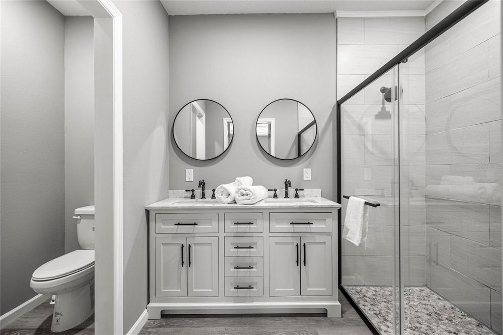 15010 Northeast 3rd Place Williston, FL 32696 - Photo 31 of 32 a bathroom with a toilet a sink a mirror and a shower