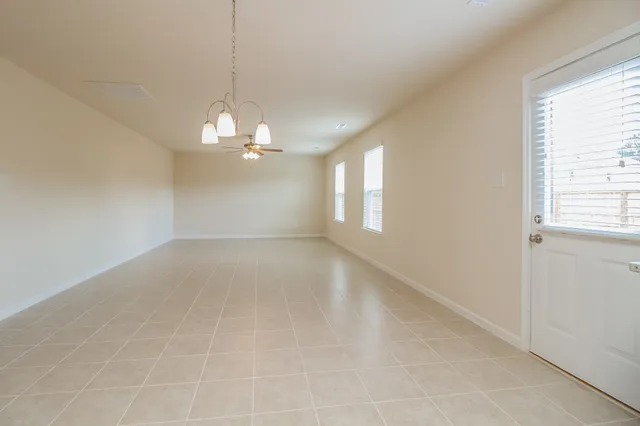 en empty room with windows and chandelier
