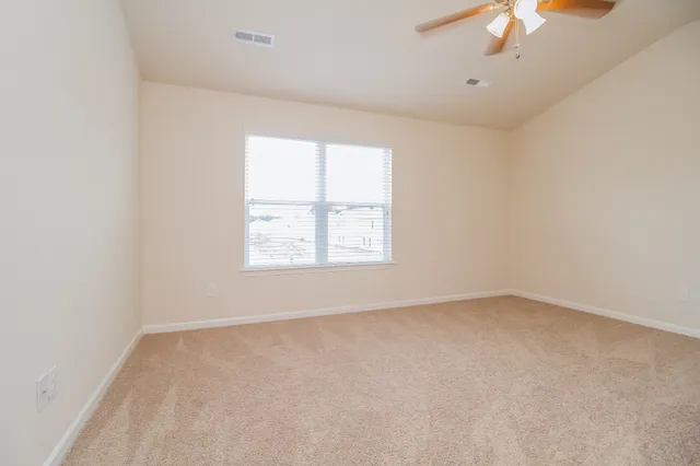 an empty room with a window and a fan