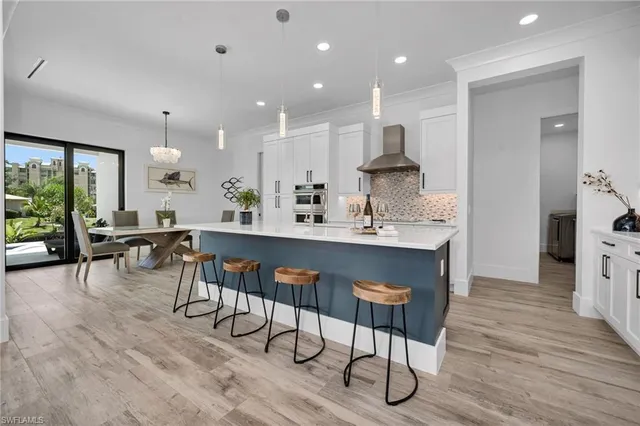 a large dining hall with stainless steel appliances granite countertop a stove a sink a dining table and chairs with wooden floor