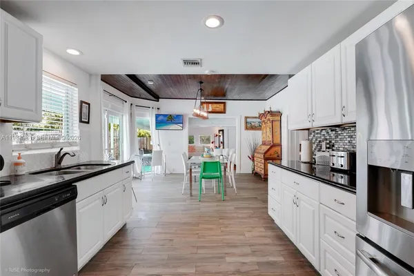 a kitchen with stainless steel appliances granite countertop a stove a sink and a refrigerator with wooden floors