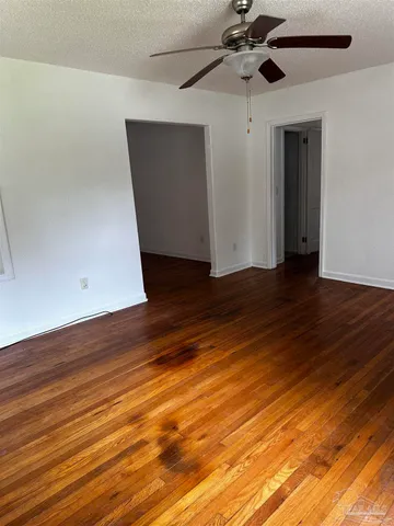 an empty room with wooden floor chandelier fan and windows