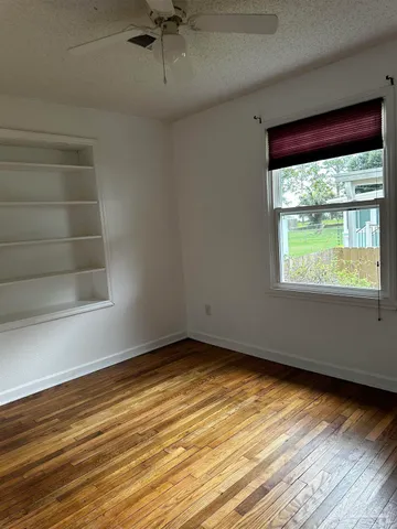 a view of an empty room with a window and wooden floor