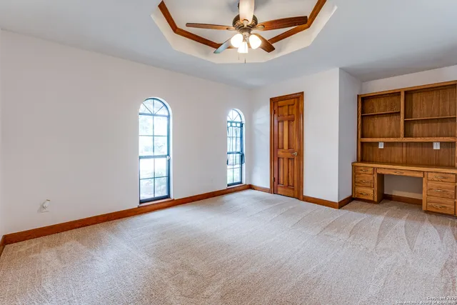an empty room with windows and ceiling fan