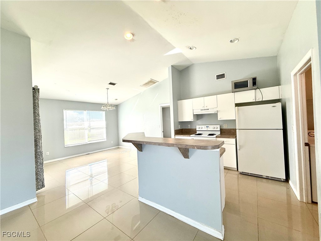 2911 40th Street Southwest Lehigh Acres, FL 33976 - Photo 5 of 22 a kitchen with a refrigerator a stove top oven and a counter space